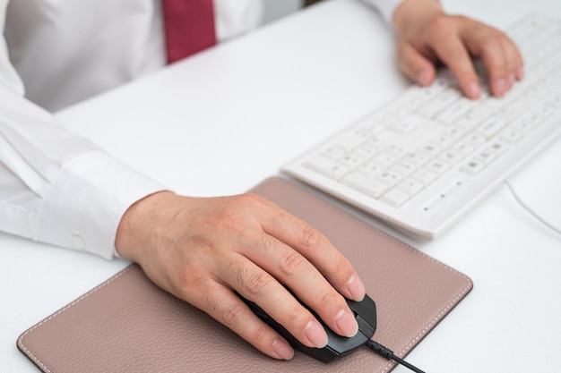 Mano del hombre de negocios que sostiene el ratón de la computadora en el escritorio de la oficina