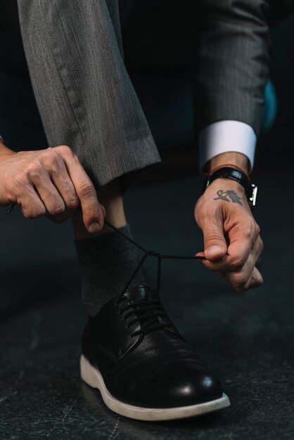 Foto la mano del hombre de negocios de la sección baja atando el cordón de los zapatos