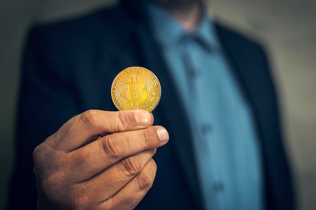 La mano de un hombre de negocios sostiene una moneda de bitcoin en un espacio de fondo gris para el concepto de dinero futuro de texto y vi