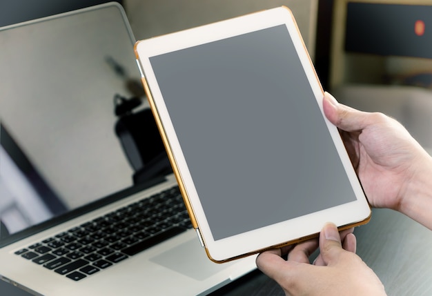 Mano de hombre de negocios con una tableta blanca con pantalla en blanco en la oficina.