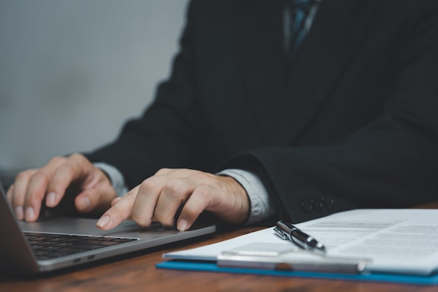 Mano de hombre de negocios trabaja en la computadora portátil con teclado en la mesa de la oficina cerca del concepto de negocio y tecnología