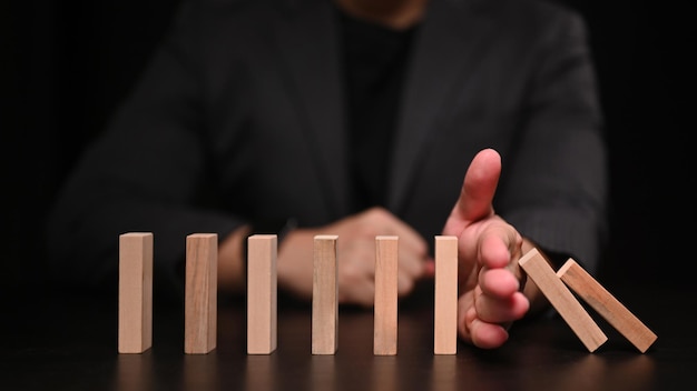 Foto mano de hombre de negocios tratando de detener el dominó finanzas de protección del concepto de efecto dominó