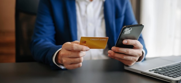 Mano de hombre de negocios usando pagos de tableta de teléfono inteligente y sosteniendo tarjeta de crédito compras en línea omnicanal tableta digital acoplando computadora con teclado