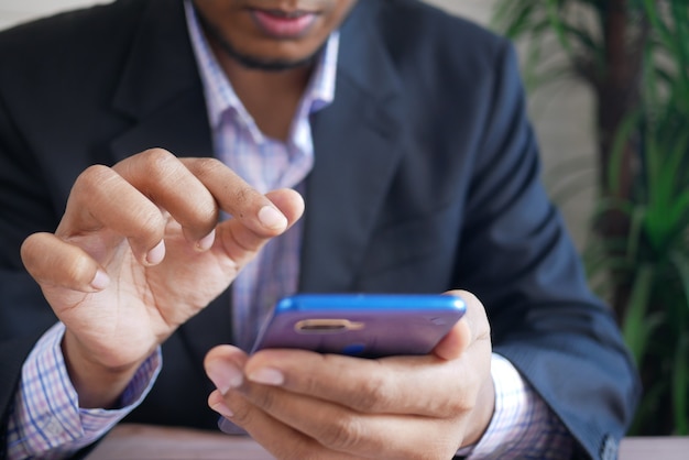 Foto mano de hombre de negocios usando un teléfono inteligente mientras está ubicado