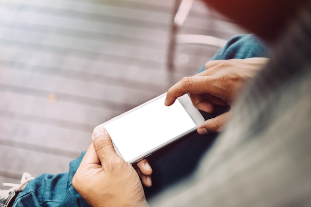 Mano de hombre de negocios usando el teléfono móvil en la cafetería en la luz de la mañana