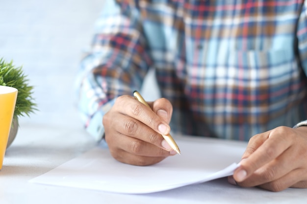 Mano de hombre en pluma estilográfica escribiendo o firma en papel