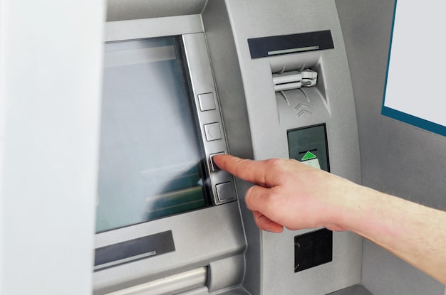 La mano del hombre pone el botón gris de la tarjeta ATM