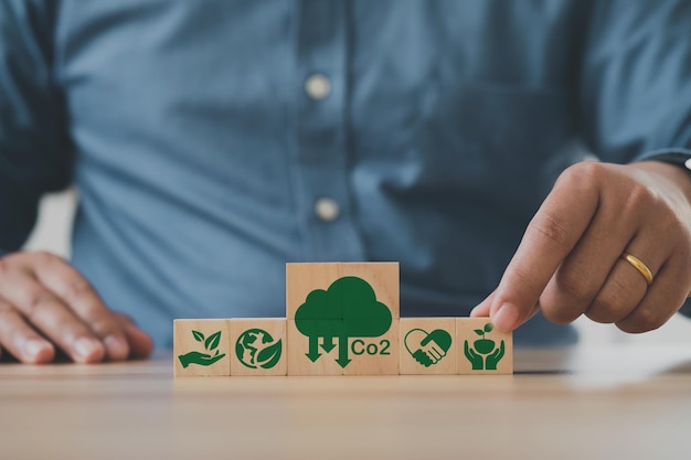 Foto la mano del hombre pone los cubos de madera con el icono de reducción de emisiones de co2 concepto de emisión de co2 concepto de negocio de industrias verdes