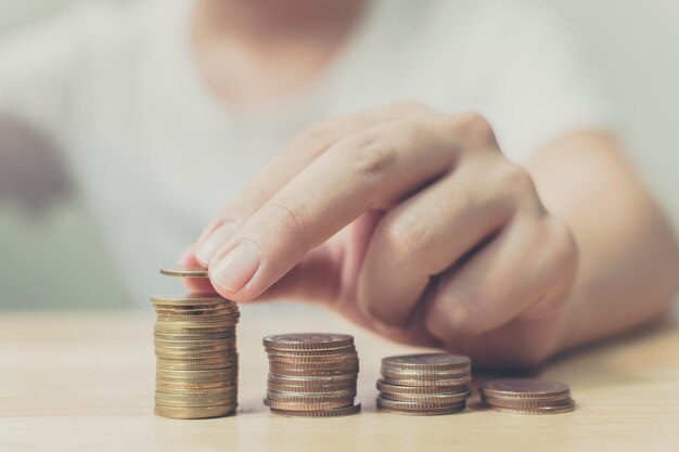 Mano de hombre poniendo pila de monedas de oro Finanzas e inversión concepto de ahorro de dinero