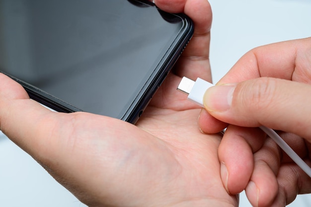 Mano del hombre que conecta el cable typec al teléfono inteligente