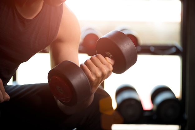 Mano del hombre que lleva a cabo ejercicio de la pesa de gimnasia en gimnasio. Ejercicio físico del cuerpo muscular