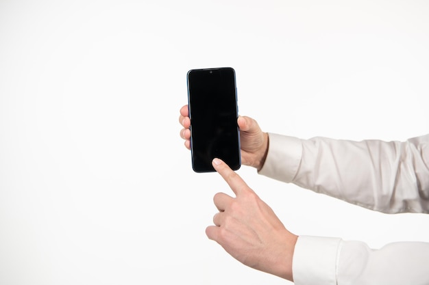 Mano del hombre que presenta la pantalla del teléfono. Señalar con el dedo en la pantalla del teléfono inteligente aislado en blanco