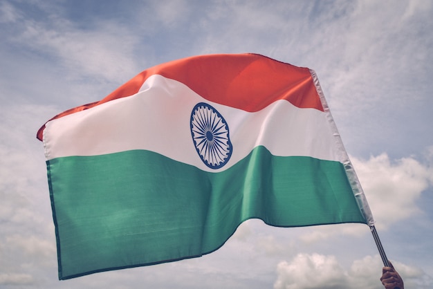 Mano del hombre que sostiene la bandera de la India en el cielo azul