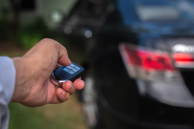 Mano de un hombre que sostiene y empuja el control remoto del automóvil negro, concepto de seguridad del transporte tecnológico