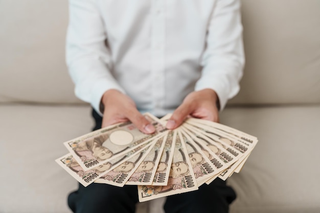 Mano de hombre que sostiene la pila de billetes de yen japonés Dinero de mil yenes Japón efectivo Recesión fiscal Economía Inflación Finanzas de inversión y conceptos de pago de compras