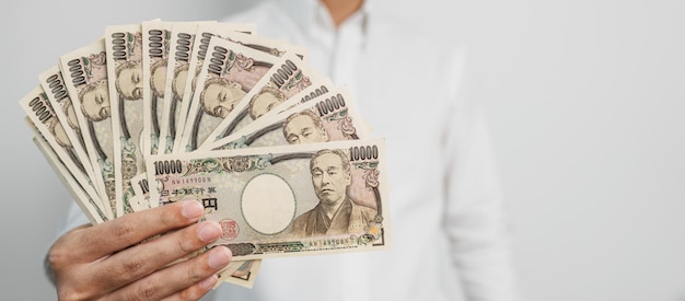 Mano de hombre que sostiene la pila de billetes de yen japonés Dinero de mil yenes Japón efectivo Recesión fiscal Economía Inflación Finanzas de inversión y conceptos de pago de compras