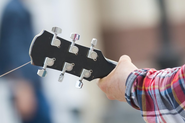 Mano del hombre que toca la guitarra acústica en la calle