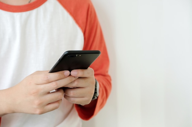 Mano del hombre que usa el teléfono elegante negro sobre el fondo blanco