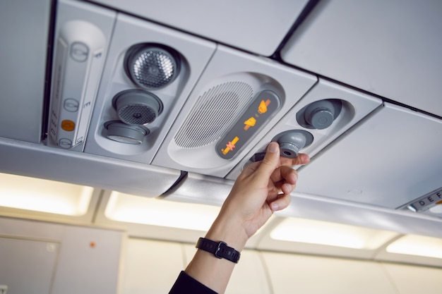 La mano del hombre regula el aire y la luz en el avión en el panel de instrumentos de arriba