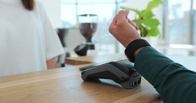 Mano de hombre con reloj inteligente usando terminal para pago vista lateral de transacciones sin efectivo Concepto de pago sin efectivo Posterminal en la mesa sobre fondo negro