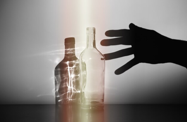 Mano del hombre con silueta de botella de alcohol. Adicto al alcohol. Hábito peligroso. Concepto de vida malsana. Problema social.