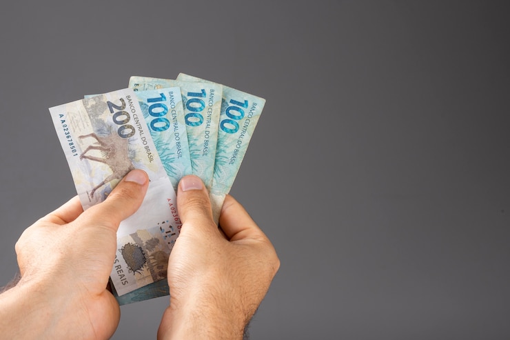 Foto mano de un hombre sosteniendo billetes de reales brasileños