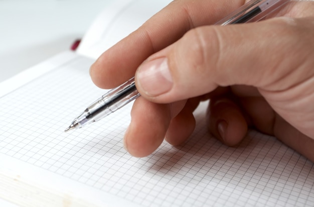 Mano del hombre sosteniendo un bolígrafo y listo para escribir en el cuaderno