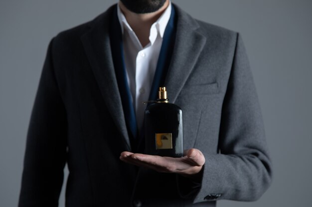 Foto mano de hombre sosteniendo la botella de perfume
