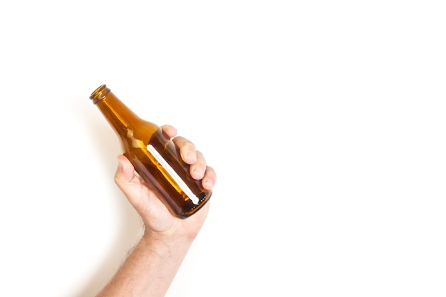 Foto mano de hombre sosteniendo una botella vacía de cerveza sobre un fondo blanco.