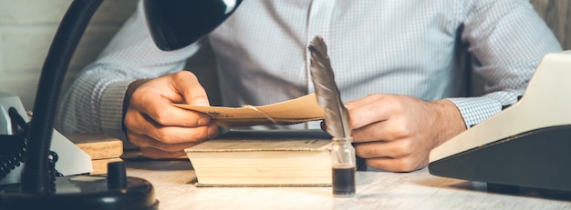 Mano de hombre sosteniendo letras en el libro en el escritorio