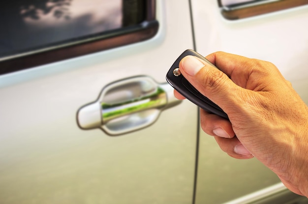 Mano de hombre sosteniendo la llave del auto lista para arrancar un auto nuevo con un fondo de auto borroso