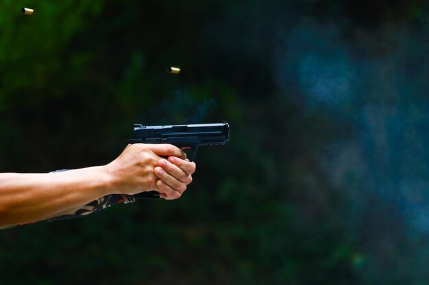 Foto mano de hombre sosteniendo la pistola con fondo oscuro