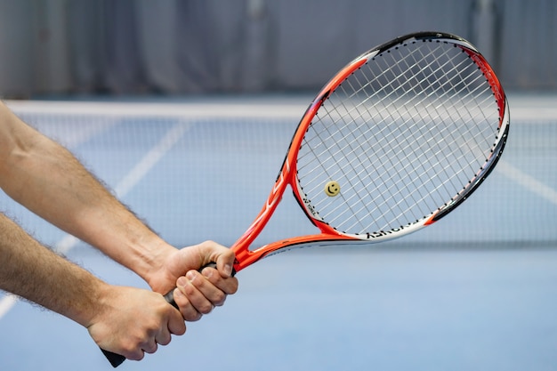 La mano del hombre sosteniendo la raqueta de tenis en la cancha de tenis