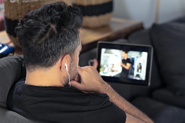 Mano de hombre sosteniendo con tableta digital viendo la clase magistral de cocina en línea