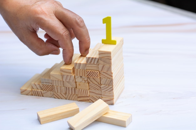 Foto mano del hombre sosteniendo una tapa de bloques de madera sobre bloque de madera