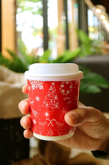 Mano de hombre sosteniendo una taza de café para llevar rojo y blanco