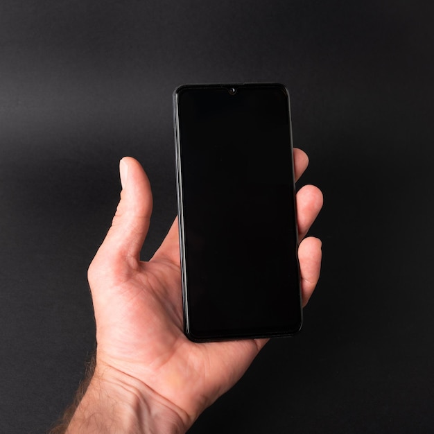 Foto mano de hombre sosteniendo un teléfono en una plantilla de fondo negro