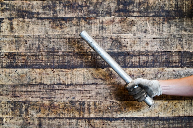 Mano de hombre sosteniendo varilla de metal sobre fondo de madera