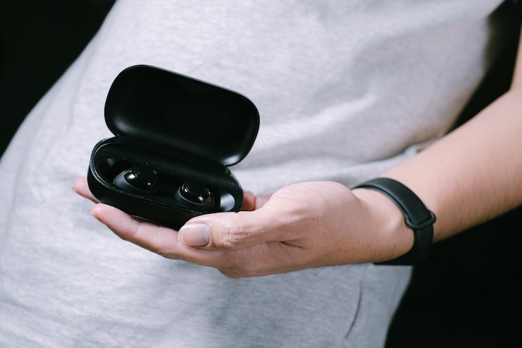 La mano del hombre sostiene auriculares inalámbricos negros en el estuche de carga