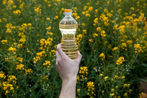 La mano de un hombre sostiene una botella de aceite de colza