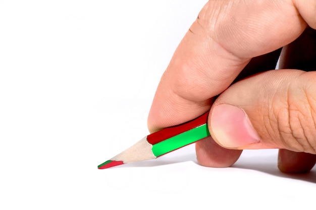 Foto una mano de hombre sostiene un lápiz verde sobre el escritorio blanco, mesa, tablero blanco aislado en el estudio. lápiz bicolor y verde y rojo. lápices con doble colo