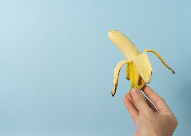 Mano de un hombre sostiene plátano con un espacio de copia.