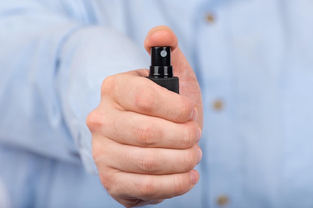 La mano del hombre sostiene un spray antibacteriano protector Vista frontal Cerrar