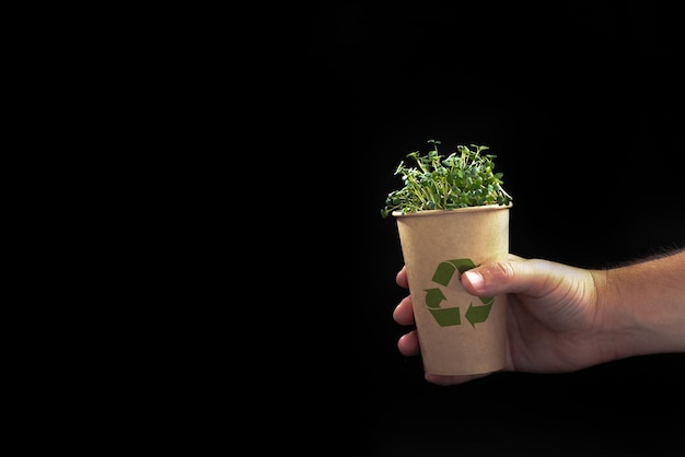 La mano de un hombre sostiene una taza de kraft con verduras dentro del concepto de reciclar la vida sin una copia de plástico