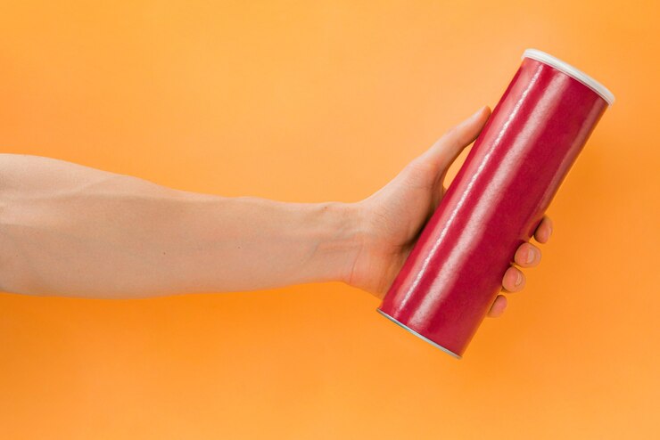 La mano del hombre sostiene un tubo en blanco rojo de chips sobre un fondo naranja Mockup de papas fritas Mock up