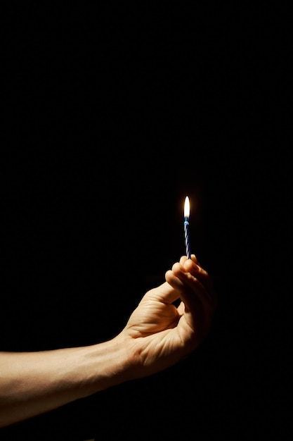Foto la mano del hombre sostiene una vela encendida la vela ilumina el cuarto oscuro
