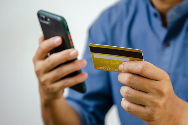 Mano de hombre con tarjeta de crédito y teléfono móvil compras en línea comercio electrónico y banca por Internet