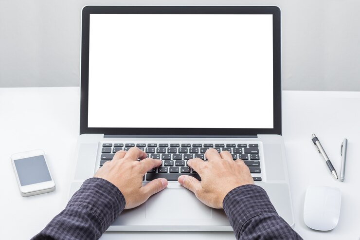 Foto mano de hombre en el teclado del ordenador portátil con monitor de pantalla en blanco