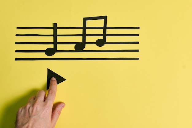 Foto la mano de un hombre toca el botón de reproducción sobre un fondo amarillo. concepto de musica