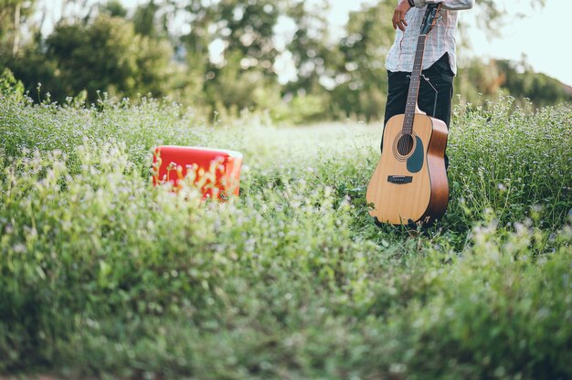 La mano del hombre toca la guitarra acústica, toca la guitarra solo en el jardín